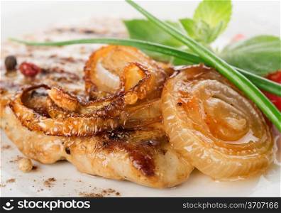 Pork steak with fried onion on a white plate close-up