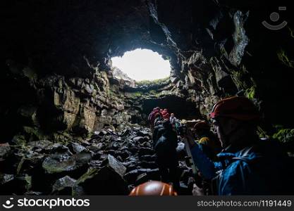 Porlakshafnarvegur, Iceland - July 3, 2018: Group of people and tourists explore Raufarholshellir lava tunnel cave in Iceland. The cave was naturally formed by magma solidification.