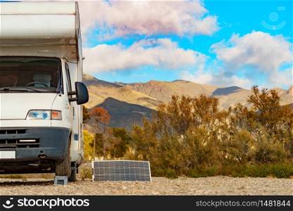 Portable solar photovoltaic panel, charging battery at camper car rv. Sierra Alhamilla mountain range landscape.. Solar photovoltaic panel at camper caravan