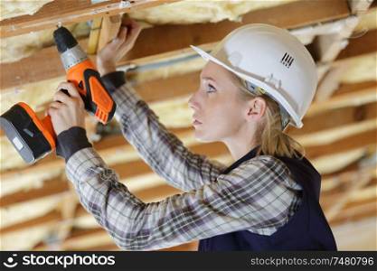 portait of a female worker drilling ceiling
