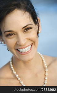 Portait of Caucasian mid-adult woman in pearls smiling and looking at viewer.