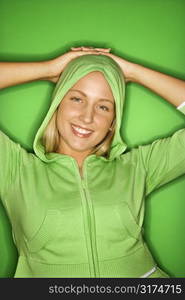 Portait of Caucasian teen girl wearing hooded sweatshirt leaning back with hands behind head and smiling.