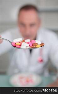 portait of senior holdiong medical pills on teaspoon