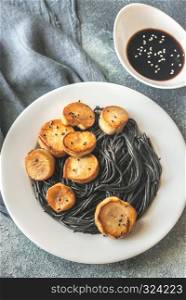 Portion of black pasta with king oyster scallops