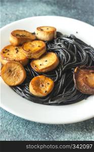 Portion of black pasta with king oyster scallops