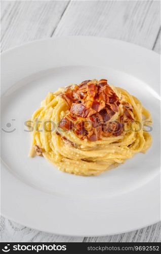 Portion of carbonara pasta garnished with fried guanciale
