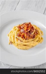 Portion of carbonara pasta garnished with fried guanciale