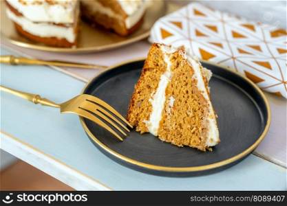Portion of carrot cake with sweet frosty, pieces of nuts and golden cutlery