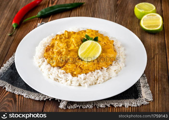 Portion of chicken curry garnished with rice and fresh lime