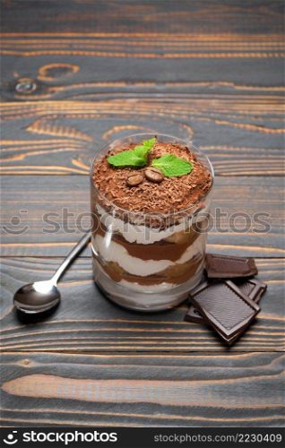 portion of Classic tiramisu dessert in a glass on wooden background or table. portion of Classic tiramisu dessert in a glass on wooden background