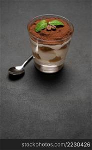 portion of Classic tiramisu dessert in a glass on wooden concrete or table. portion of Classic tiramisu dessert in a glass on concrete background