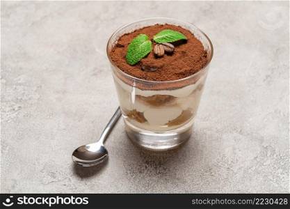 portion of Classic tiramisu dessert in a glass on wooden concrete or table. portion of Classic tiramisu dessert in a glass on concrete background