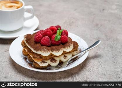 portion of Classic tiramisu dessert with raspberries and cup of coffee on grey concrete background or table. portion of Classic tiramisu dessert with raspberries and cup of coffee on grey concrete background