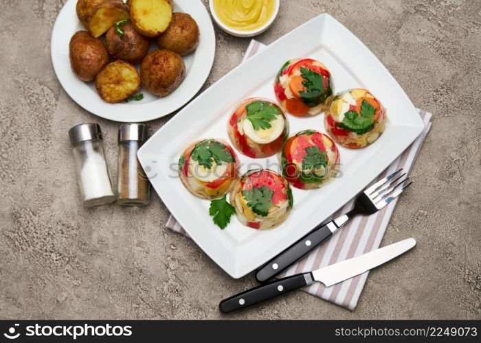 Portion of delicious chicken aspic on a plate isolated on concrete table. High quality photo. Portion of delicious chicken aspic on a plate isolated on concrete table