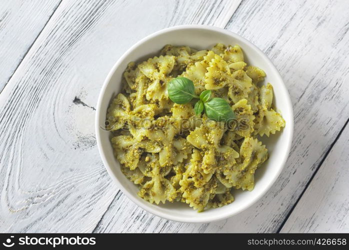Portion of farfalle with pesto on the white wooden table