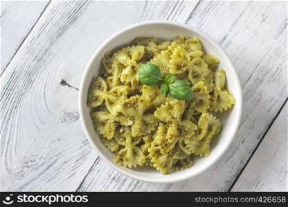 Portion of farfalle with pesto on the white wooden table