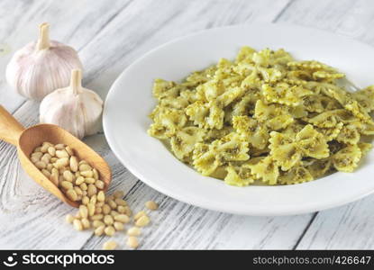 Portion of farfalle with pesto with ingredients on the white wooden table