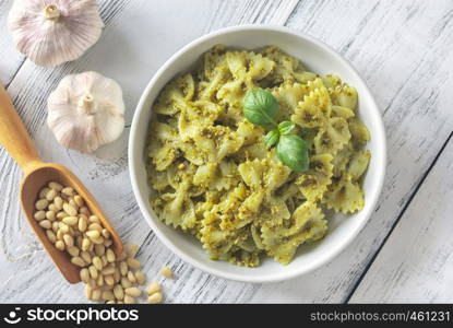 Portion of farfalle with pesto with ingredients on the white wooden table