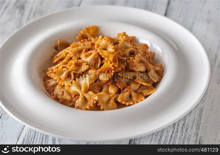 Portion of farfalle with sun-dried tomato pesto on the white wooden table