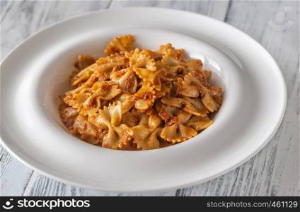 Portion of farfalle with sun-dried tomato pesto on the white wooden table