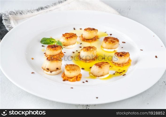 Portion of fried scallops with cauliflower puree and orange pesto sauce