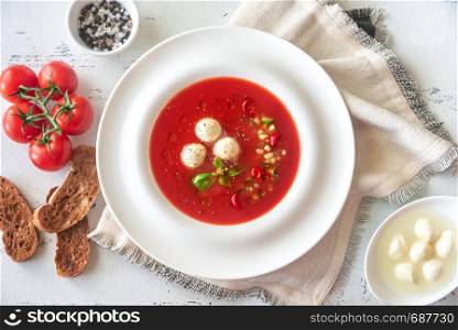 Portion of gazpacho with bocconcini on the wooden table