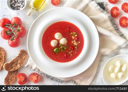 Portion of gazpacho with bocconcini on the wooden table