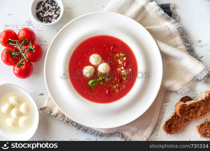 Portion of gazpacho with bocconcini on the wooden table