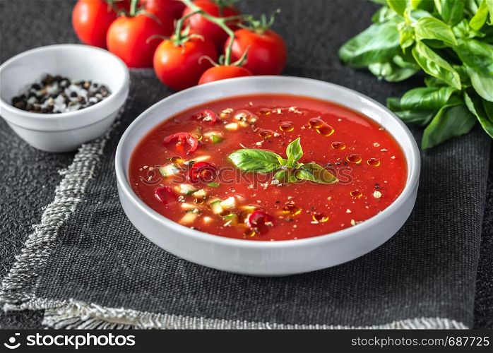 Portion of gazpacho with ingredients on the wooden table