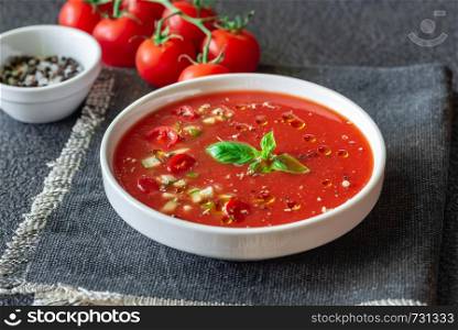 Portion of gazpacho with ingredients on the wooden table