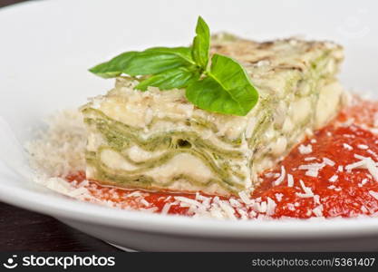 Portion of lasagna garnished with salad greens