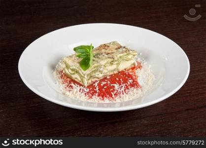 Portion of lasagna garnished with salad greens. lasagna
