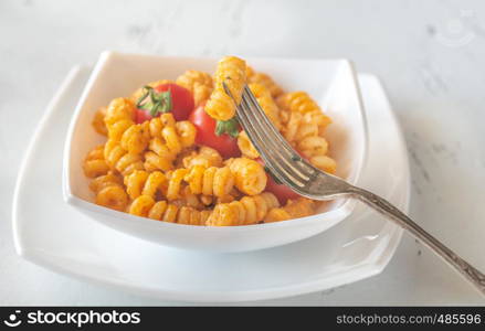 Portion of pasta with tomato and ricotta pesto on the white table