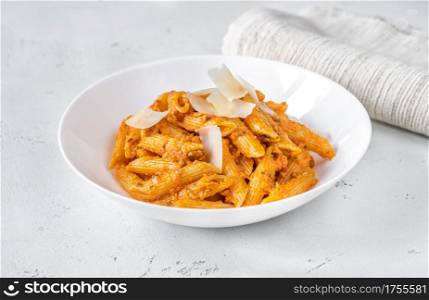 Portion of penne pasta with orange pesto sauce close up