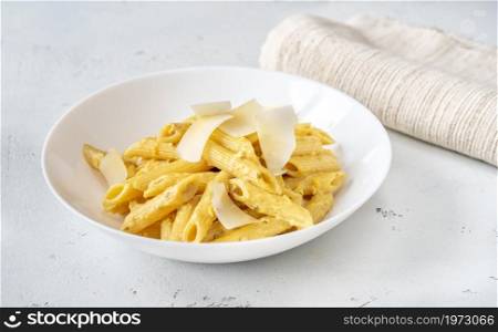Portion of penne pasta with yellow pesto sauce close up