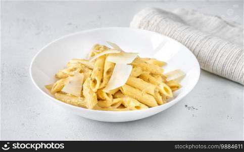 Portion of penne pasta with yellow pesto sauce close up