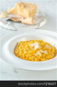 Portion of pumpkin risotto with slices of parmesan