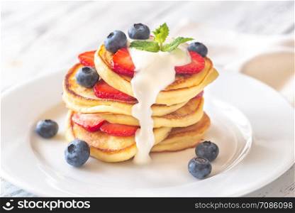 Portion of ricotta fritters with fresh strawberries and blueberries on the wooden background