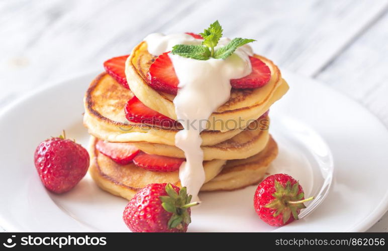 Portion of ricotta fritters with fresh strawberries and blueberries on the wooden background