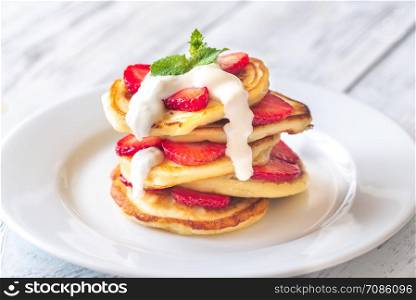Portion of ricotta fritters with fresh strawberries on the wooden background