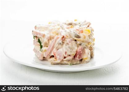 Portion of salad with ham, meat, mushrooms, vegetables and mayonnaise