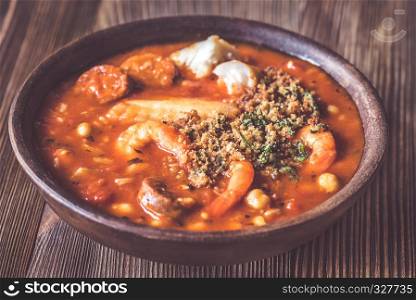 Portion of spanish fish and chorizo soup garnished with pangrattato