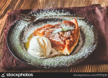 Portion of tarte Tatin decorated with fresh mint and served with ball of ice-cream