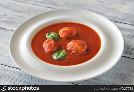 Portion of tomato soup with meatballs