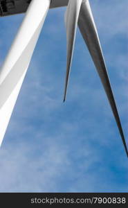 Portion of white wind turbine blades and pylon on clouds.