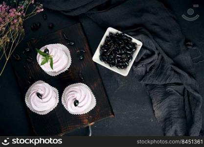 Portioned fruit marshmallows in a paper cup on a black wooden board, delicious dessert. Top view