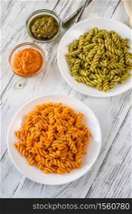 Portions of fusilli pasta with traditional and tomato pesto