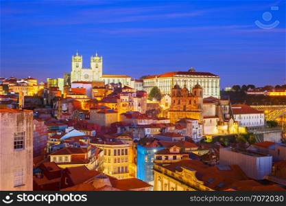 Porto Cathedral illuminated over the old town night cityscape with typical architecture and Dom Luis I, Portugal