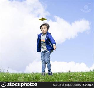 Portrait active little boy playing with toy airplane against green nature background, Child throwing foam airplane, Kid playing in the park, Childhood outdoor activity concept.