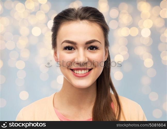 portrait and people concept - face of happy smiling young woman over holidays lights background. face of happy smiling young woman